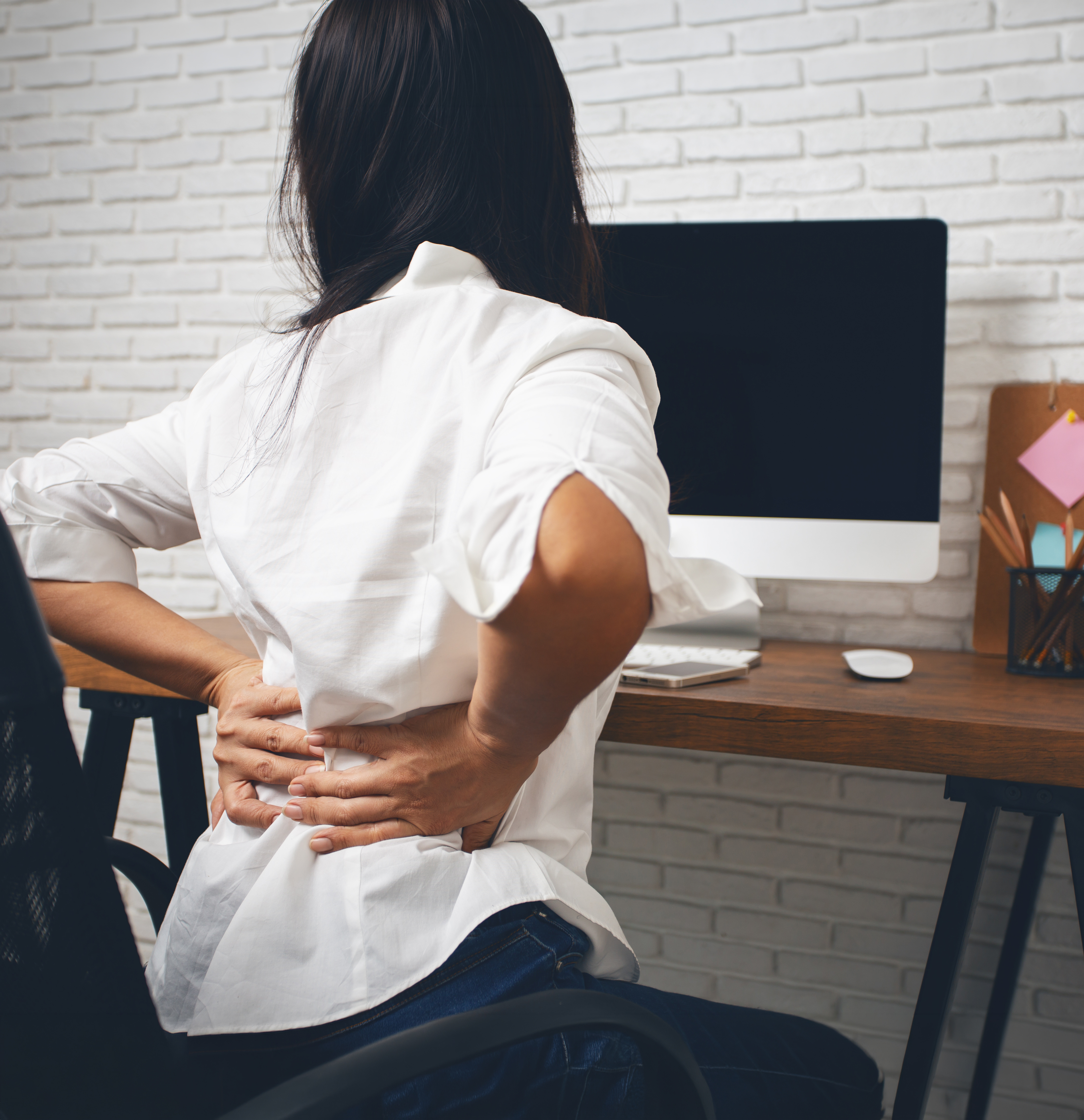 Person with back discomfort at a seated desk